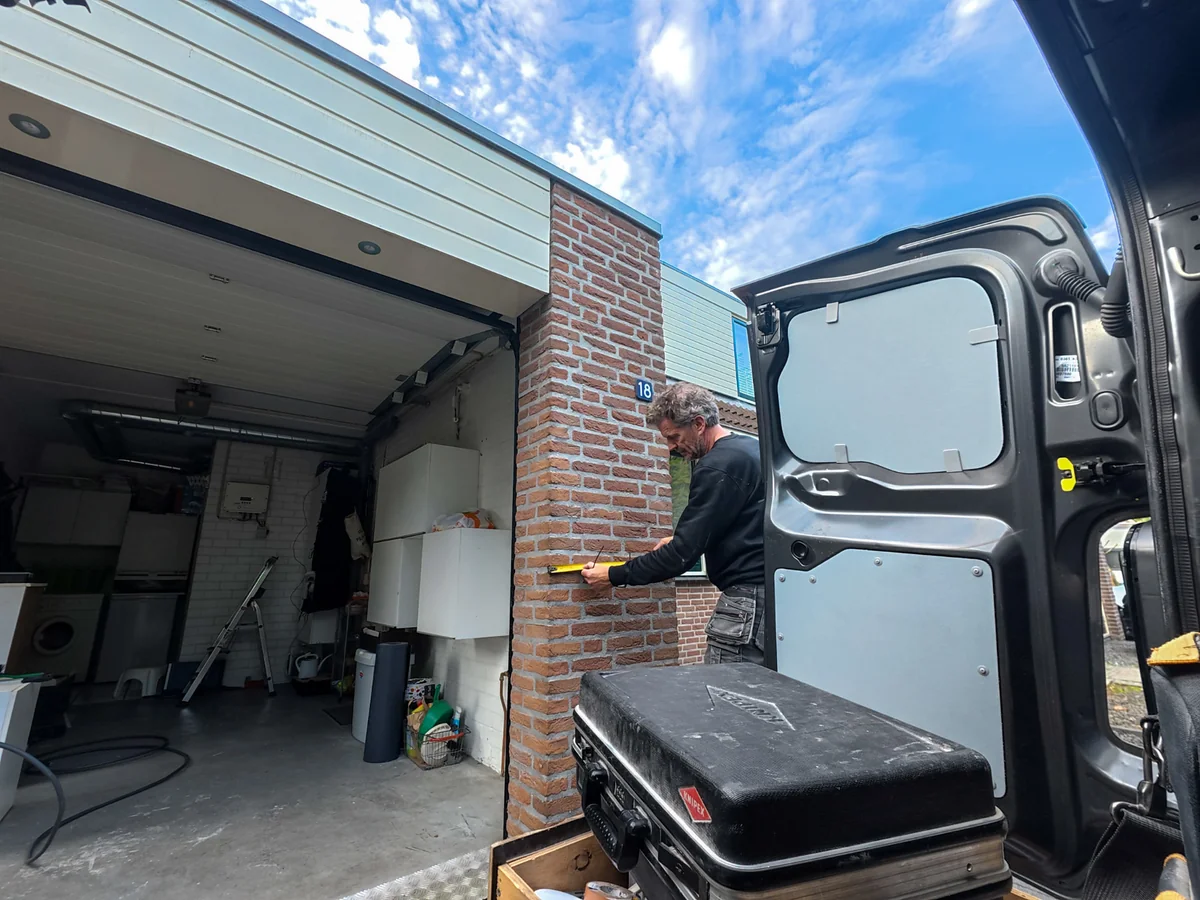 Monteur meet de positie op de bakstenen pijler bij de woning op