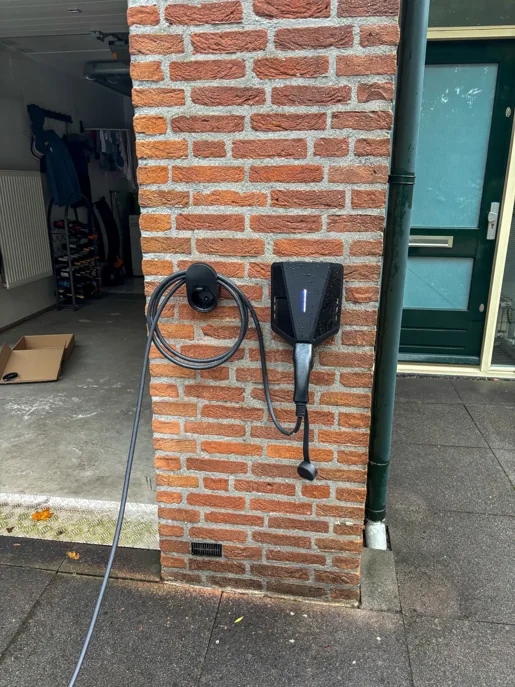 Easee Charge Max laadpaal aan de wand bij de garage, met de laadkabel aan een kabelhaak