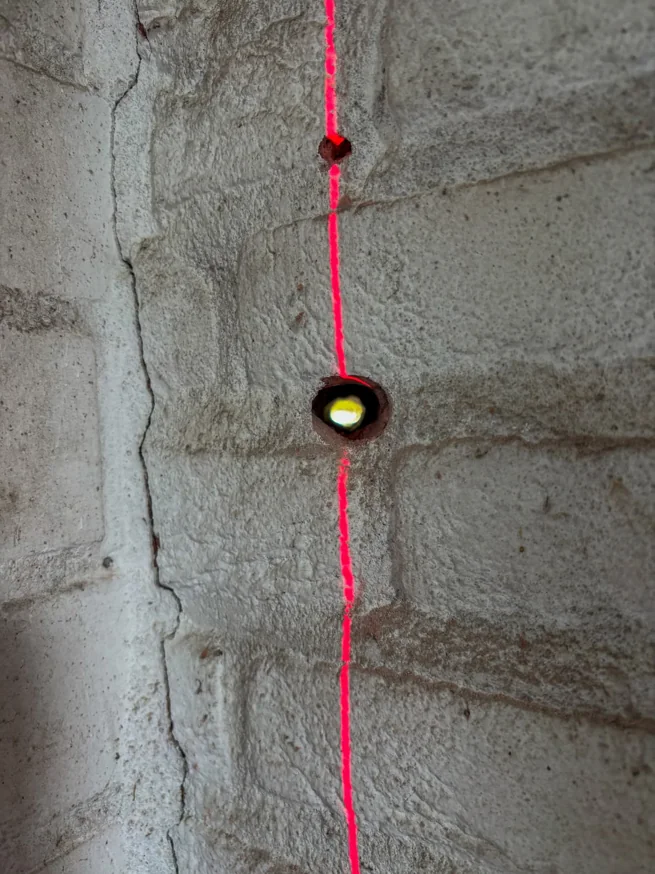 Geboorde kabeldoorvoer in de garagemuur met laserlijn