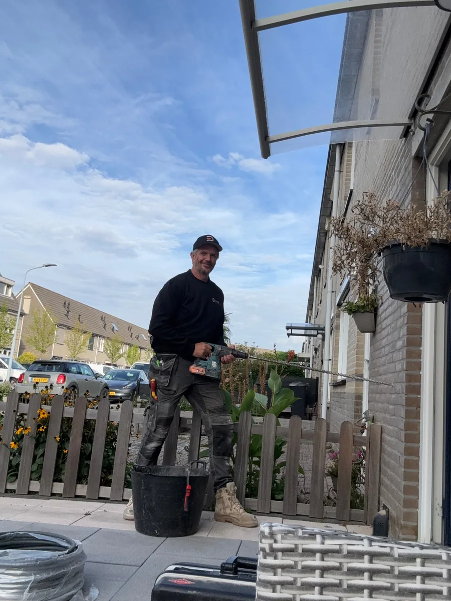 Martijn Verhulsdonck van Donck Elektrotechniek boort een gevel bij de installatie van een laadpaal
