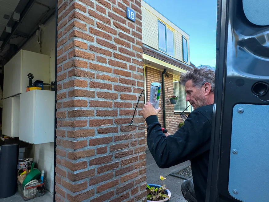 Monteur dicht de kabeldoorvoer in de garagemuur af