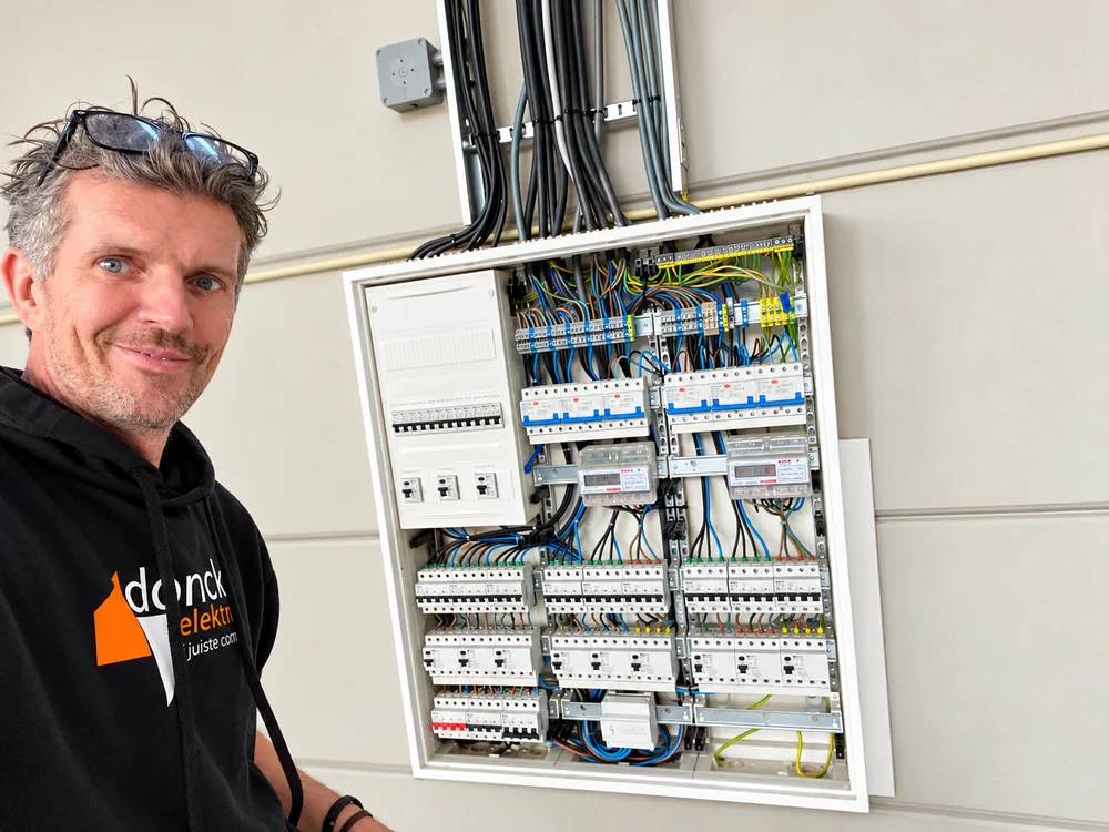 Eigenaar Martijn Verhulsdonck van Donck Elektrotechniek naast een netjes bedrade groepenkast