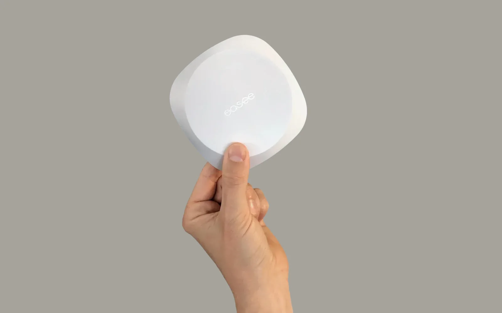 Een hand die de Easee Equalizer met twee vingers vasthoudt